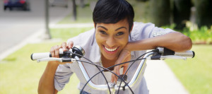 Smiling young multicultural woman leaning on her bicycle handlebars