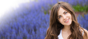 Brunette woman smiling, standing in front of a field of lavendar