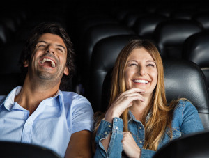 Couple laughing at the movie they're viewing, while reclining in their movie seats