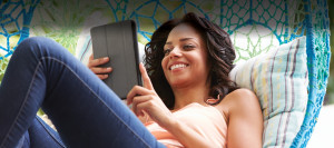 Young brunette woman relaxing in a hammock, checking her tablet device
