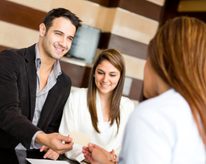 Young businessman handing his business card to young woman, his female work associate next to him