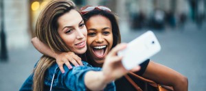 Two happy girl friends taking selfies