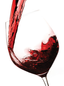 A glass of red wine being poured into a wine glass