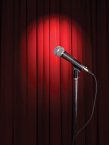 Microphone in a spotlight in front of a red velvet curtain backdrop