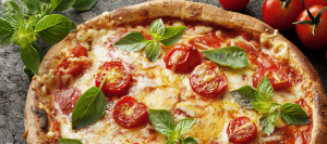 Fresh pizza with tomatoes, cheese, and fresh herbs