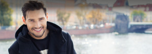 Smiling young man wearing winter coat with river in background