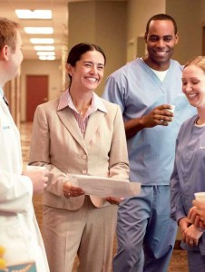 Doctor, Administrator, and medical support personnel smiling and having a discussion