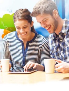 Smiling causasian couple drinking coffee and checking their tablet