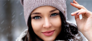 Smiling young brunette woman wearing stocking cap in snowy weather