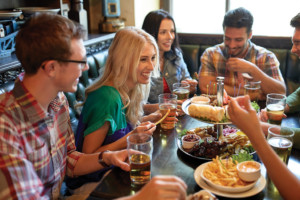 Group of young people enjoying food and drink together n a booth