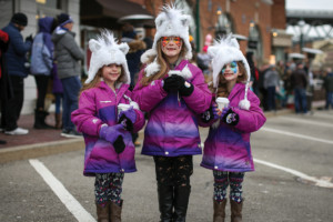 Three little girls in matching Unicorn hats, purple jackets, and colorful leggings, holding hot cocoa