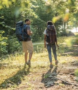 Couple backpacking through woodlands