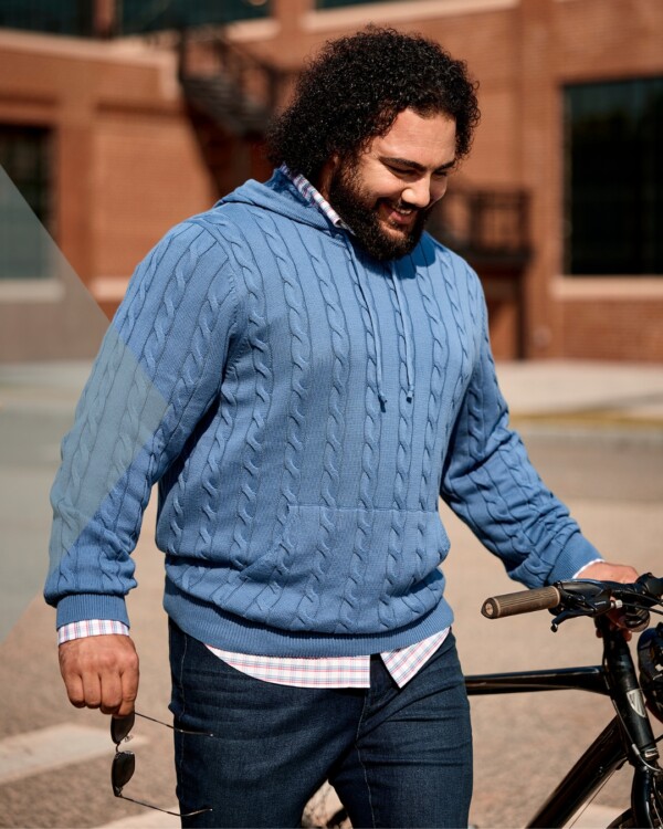 Man in sweater getting on bicycle